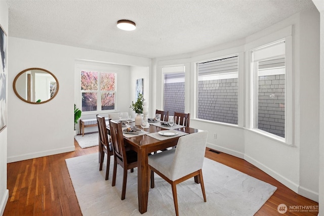 dining area featuring wood finished floors, visible vents, and baseboards