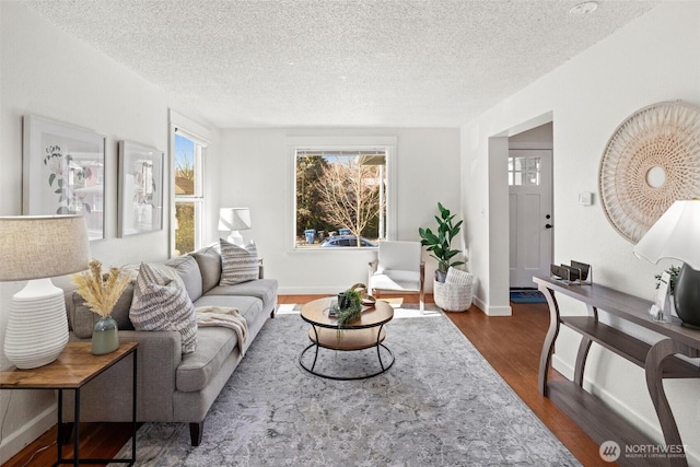 living room featuring dark wood-style floors, baseboards, and a textured ceiling