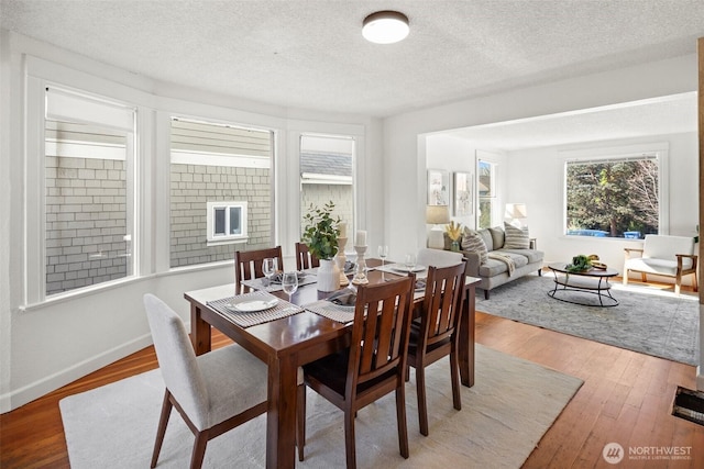 dining room featuring a textured ceiling, baseboards, and wood finished floors