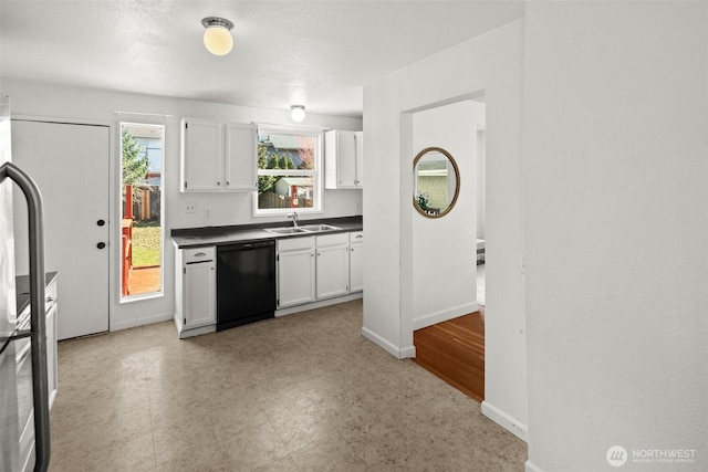 kitchen featuring dark countertops, white cabinetry, dishwasher, and a sink