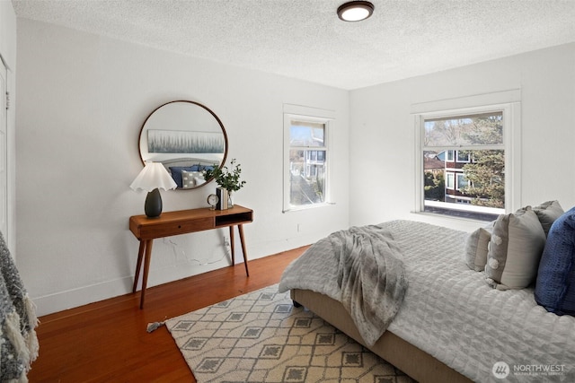 bedroom featuring baseboards, a textured ceiling, and light wood finished floors