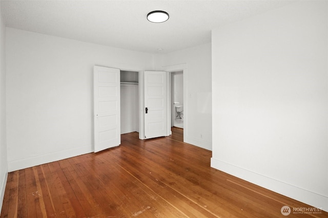 unfurnished bedroom with a closet, wood-type flooring, and baseboards