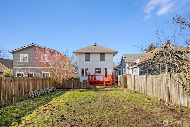 back of house featuring a deck, a lawn, and a fenced backyard