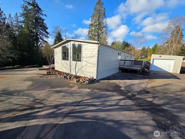 view of side of home with a garage, an outbuilding, and a deck