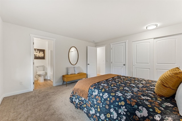 carpeted bedroom with a closet, baseboards, and ensuite bathroom