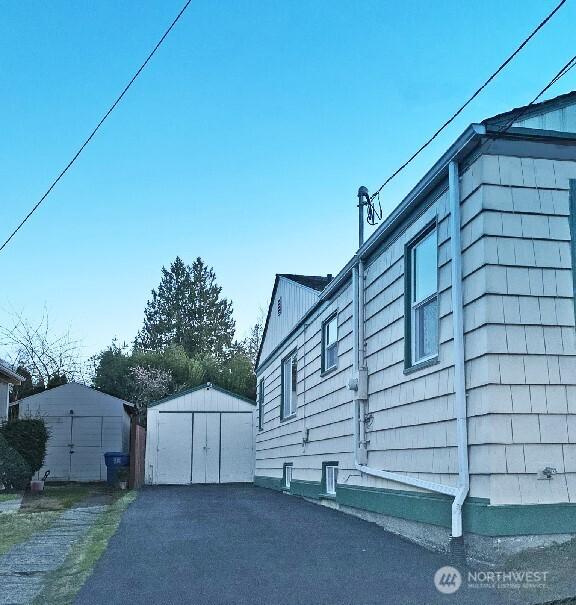 view of property exterior with a garage, an outbuilding, aphalt driveway, and a shed