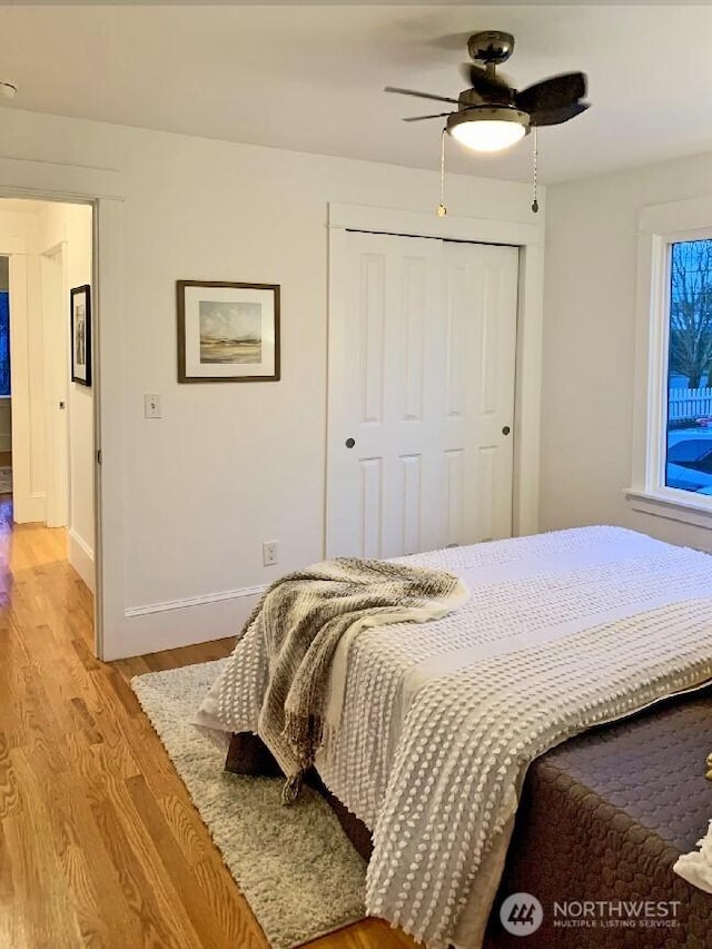 bedroom featuring a closet, baseboards, ceiling fan, and light wood finished floors