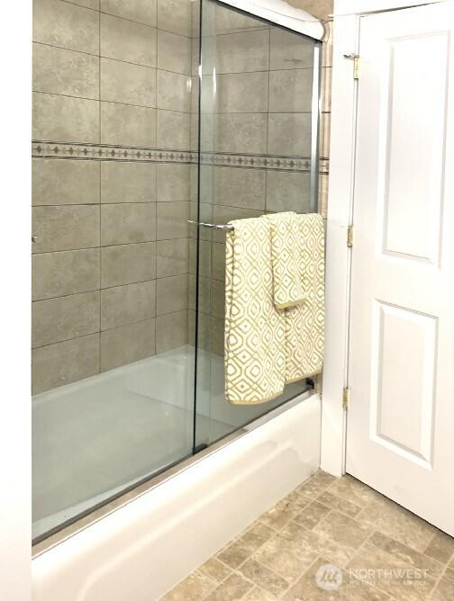 full bath featuring bath / shower combo with glass door