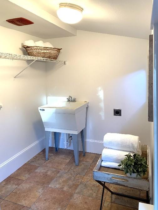 laundry area featuring laundry area, stone finish floor, and baseboards