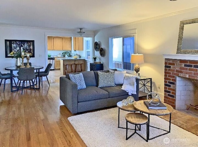 living room with light wood-style flooring, a fireplace, and ornamental molding