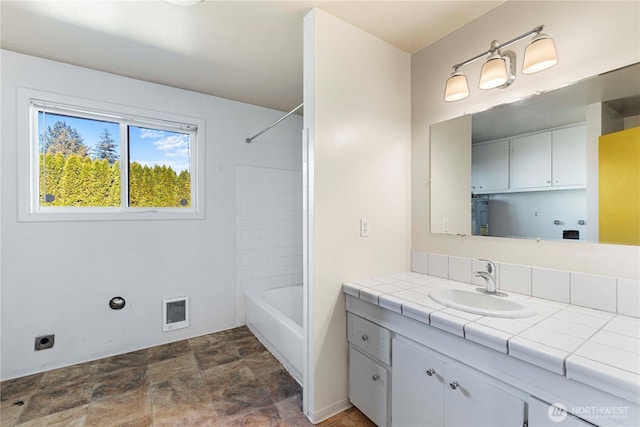 full bath featuring visible vents, baseboards, stone finish flooring, bathtub / shower combination, and vanity