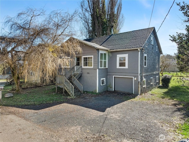 view of front facade featuring stairs, an attached garage, driveway, and a shingled roof