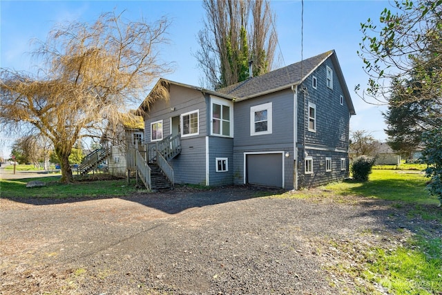 exterior space featuring stairway, an attached garage, and driveway