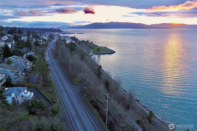 aerial view at dusk featuring a water and mountain view