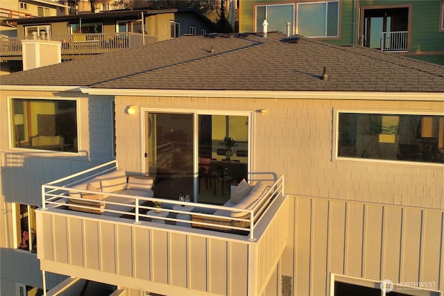 exterior space with a balcony and a shingled roof