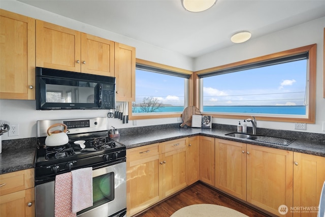 kitchen featuring dark wood finished floors, dark countertops, stainless steel gas stove, a sink, and black microwave