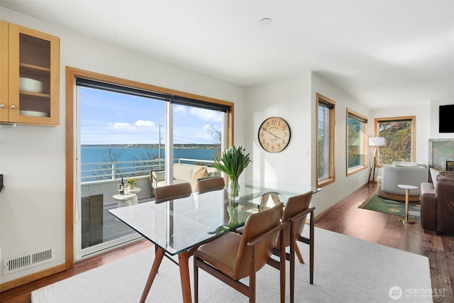 dining space featuring baseboards, visible vents, wood finished floors, and a glass covered fireplace