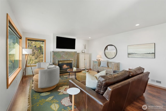 living area featuring recessed lighting, visible vents, a tiled fireplace, wood finished floors, and baseboards