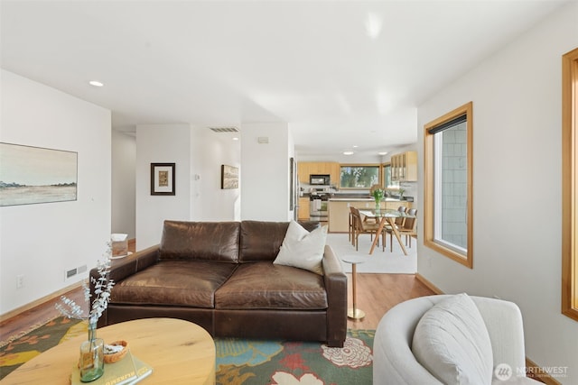 living room with light wood-style floors, baseboards, visible vents, and recessed lighting