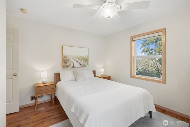 bedroom with a ceiling fan, wood finished floors, visible vents, and baseboards