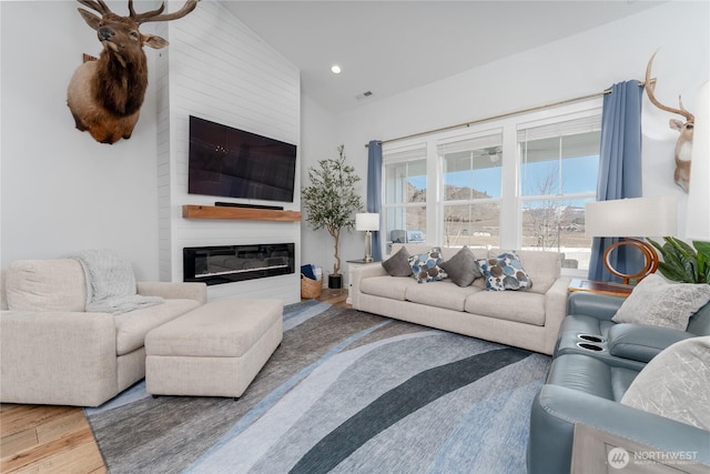 living room featuring lofted ceiling, recessed lighting, visible vents, a large fireplace, and wood finished floors