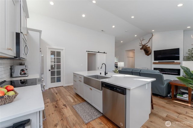 kitchen with stainless steel appliances, light countertops, a barn door, open floor plan, and a sink