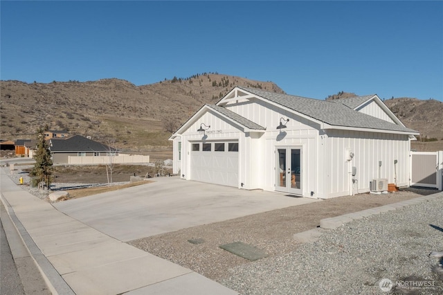 garage with driveway, fence, french doors, central air condition unit, and a mountain view