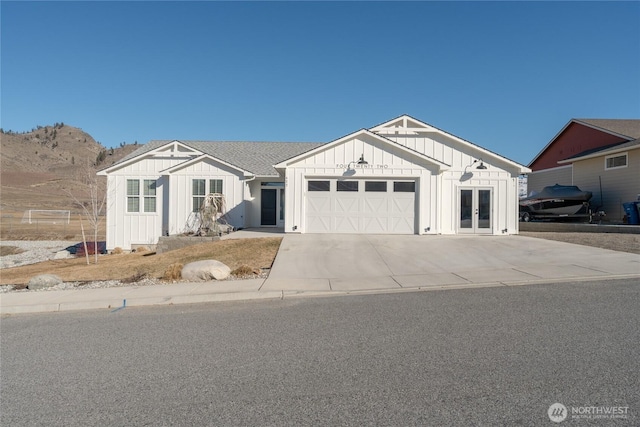 modern farmhouse with a garage, a shingled roof, concrete driveway, french doors, and board and batten siding