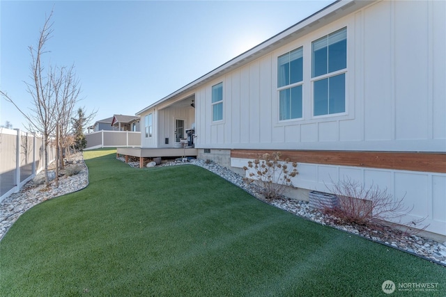 exterior space with board and batten siding, a fenced backyard, and a yard