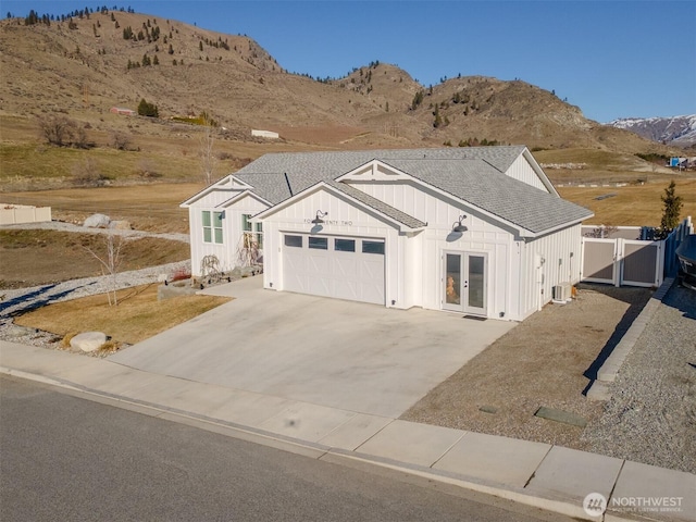 view of front of house featuring roof with shingles, a gate, french doors, a mountain view, and board and batten siding