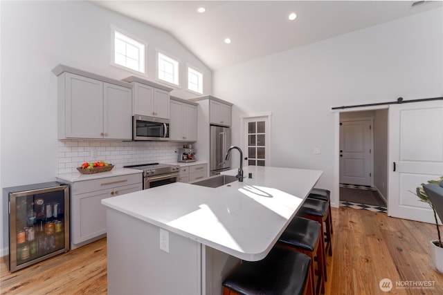 kitchen with premium appliances, a barn door, a sink, beverage cooler, and a kitchen breakfast bar