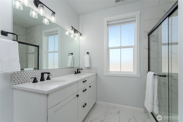 full bath featuring baseboards, decorative backsplash, marble finish floor, a shower stall, and a sink