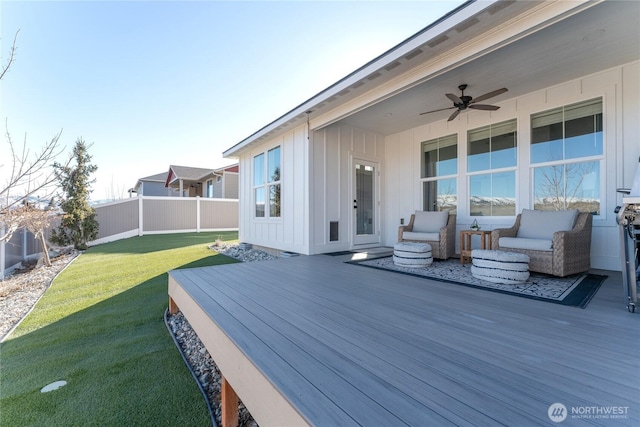 wooden deck with a lawn, fence, outdoor lounge area, and a ceiling fan