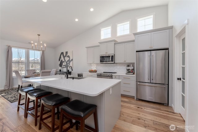 422 Sunny Brooke Ln, Chelan, WA 98816 - kitchen with stainless steel appliances, a kitchen island with sink, a breakfast bar, light wood-type flooring, and high vaulted ceiling