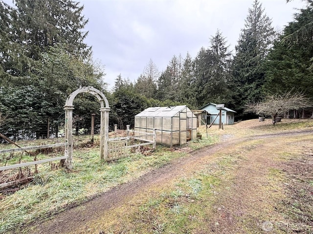 view of yard featuring an outbuilding, a garden, an exterior structure, and fence