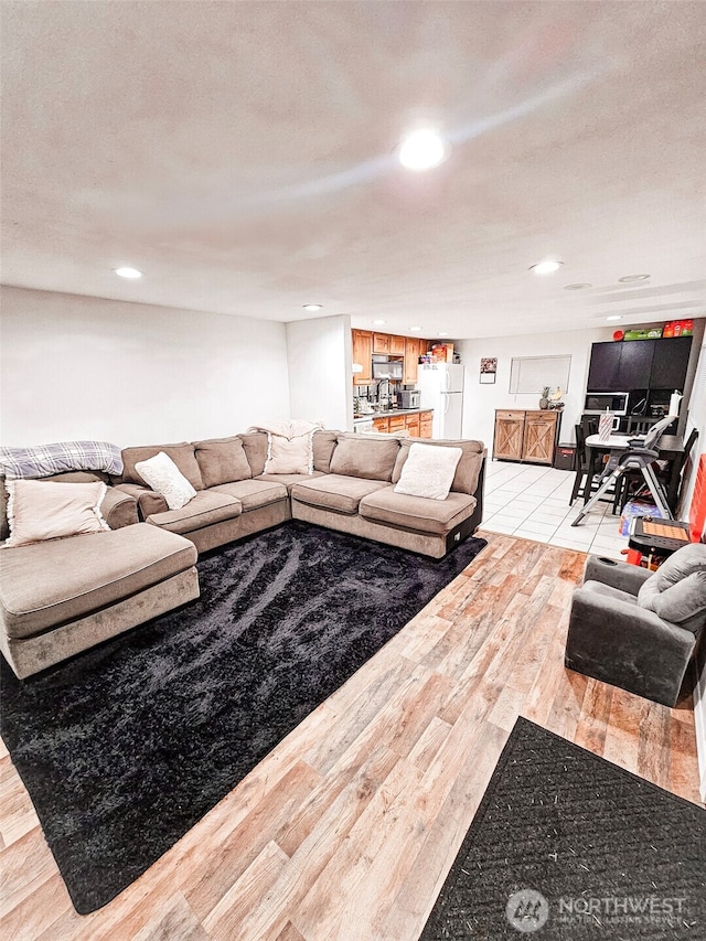 living room featuring light wood finished floors, a textured ceiling, and recessed lighting