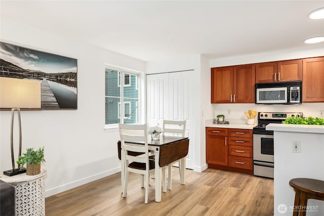 kitchen featuring stainless steel range with electric stovetop, brown cabinetry, light countertops, and light wood-style floors