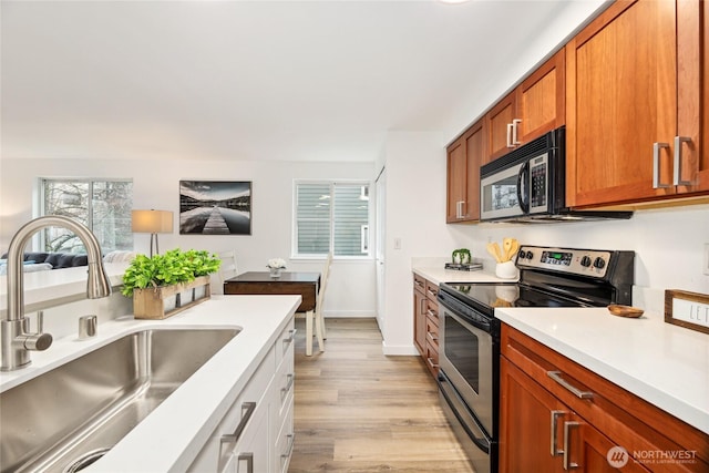 kitchen with stainless steel electric stove, a sink, light countertops, light wood-type flooring, and brown cabinets