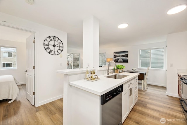 kitchen featuring a sink, light wood-style floors, light countertops, and dishwasher