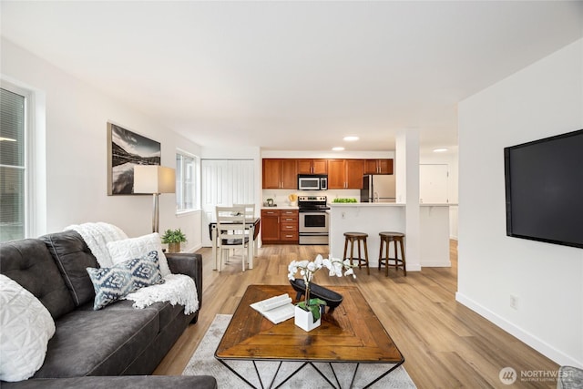 living room featuring light wood-type flooring, baseboards, and recessed lighting