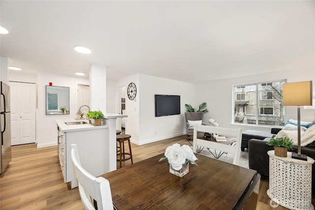 dining area with light wood-type flooring and baseboards