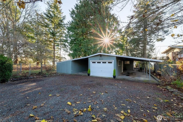 garage featuring gravel driveway and fence