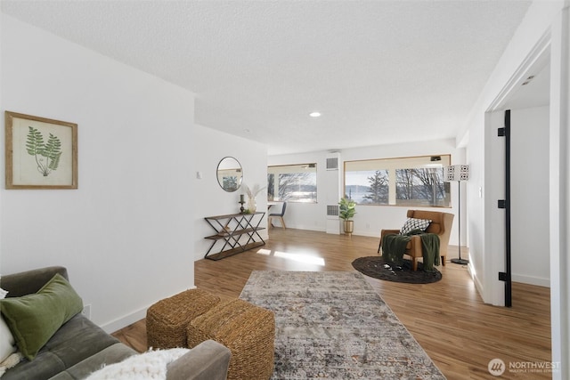 living room with visible vents, baseboards, and wood finished floors