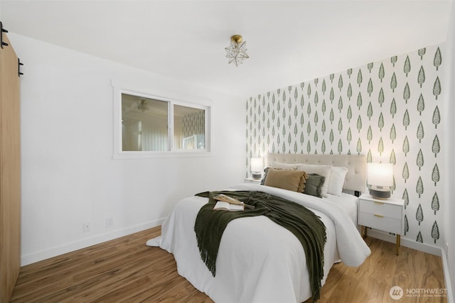 bedroom with wallpapered walls, baseboards, and wood finished floors