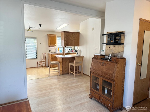 kitchen featuring light wood-style flooring, a center island with sink, a breakfast bar area, and light countertops