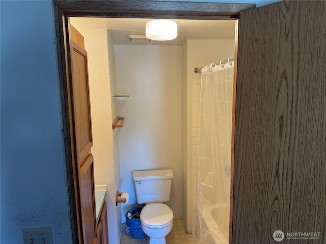 bathroom featuring toilet and shower / tub combo with curtain