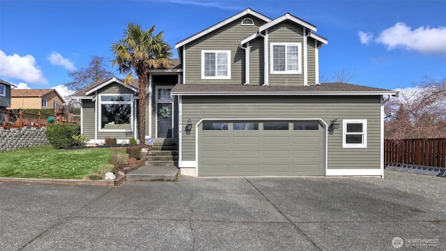 traditional-style house featuring a garage, fence, driveway, and a front lawn