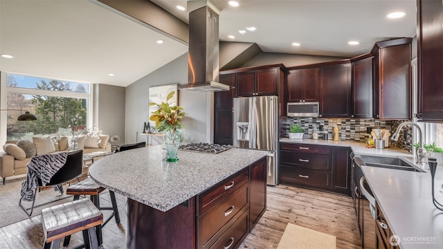 kitchen featuring stainless steel appliances, tasteful backsplash, vaulted ceiling, a sink, and island range hood