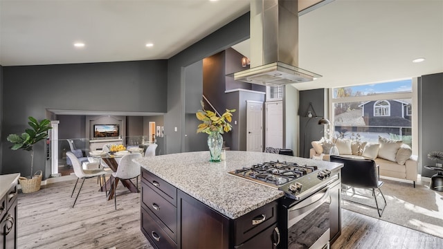 kitchen featuring stainless steel range with gas stovetop, light wood-style flooring, island range hood, and light stone countertops