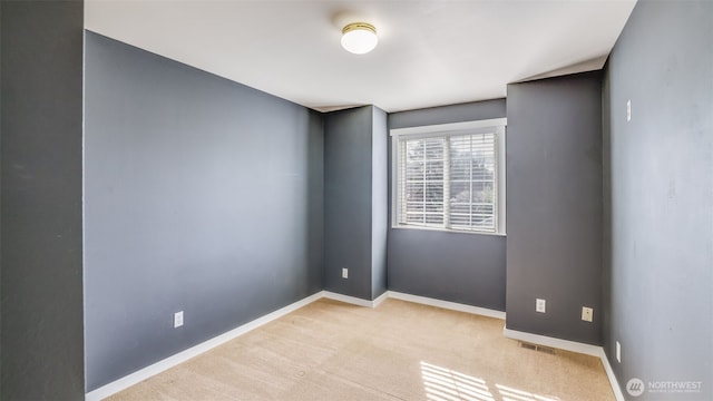 carpeted empty room featuring baseboards